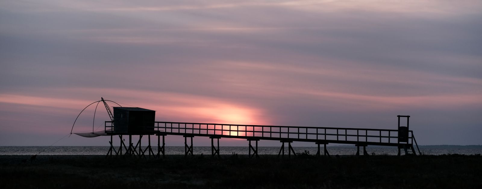 Beautiful sunset over a fishing pier in Les Moutiers-en-Retz, France.