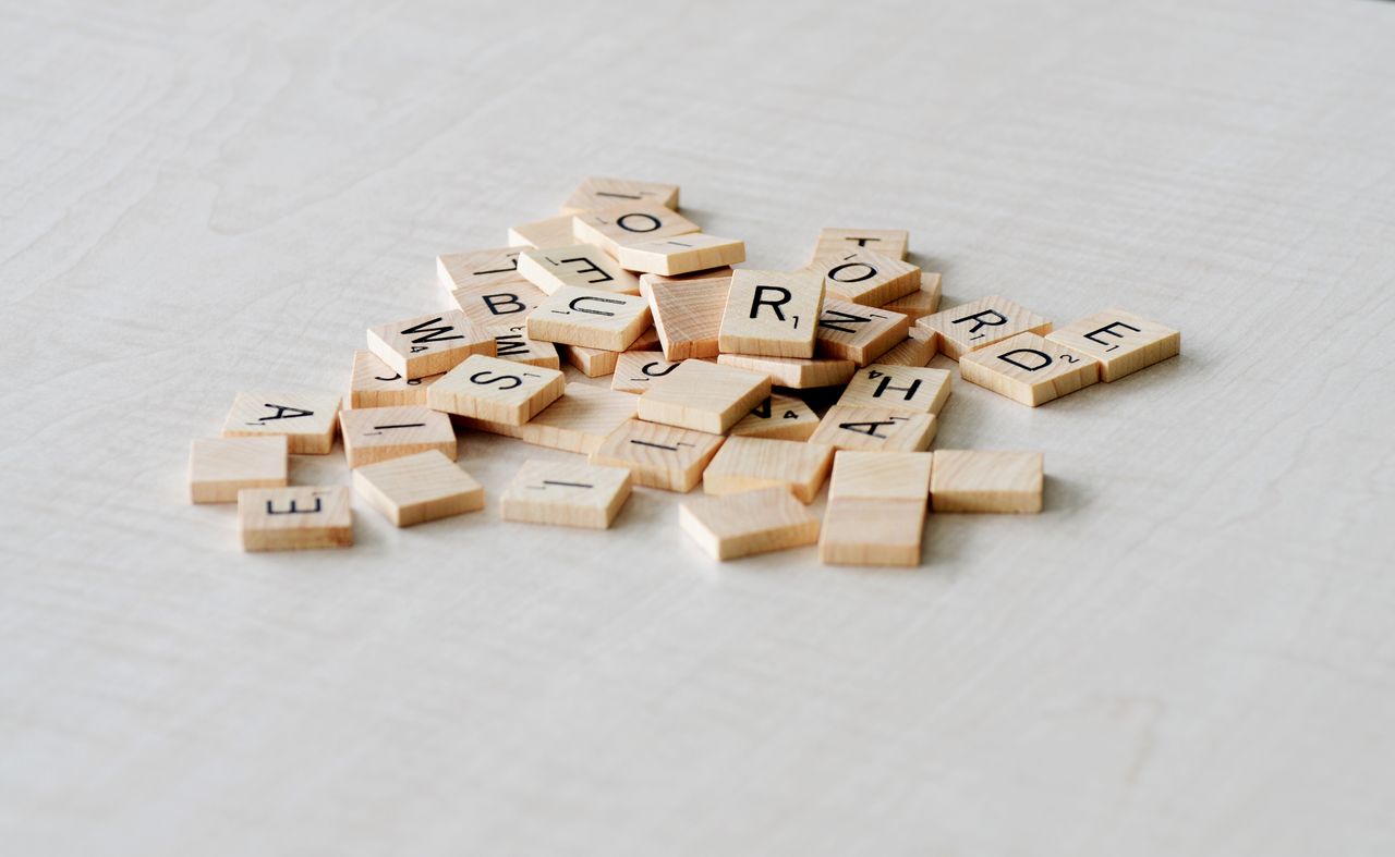 close up of wooden letter tiles scattered on a light table surface ide