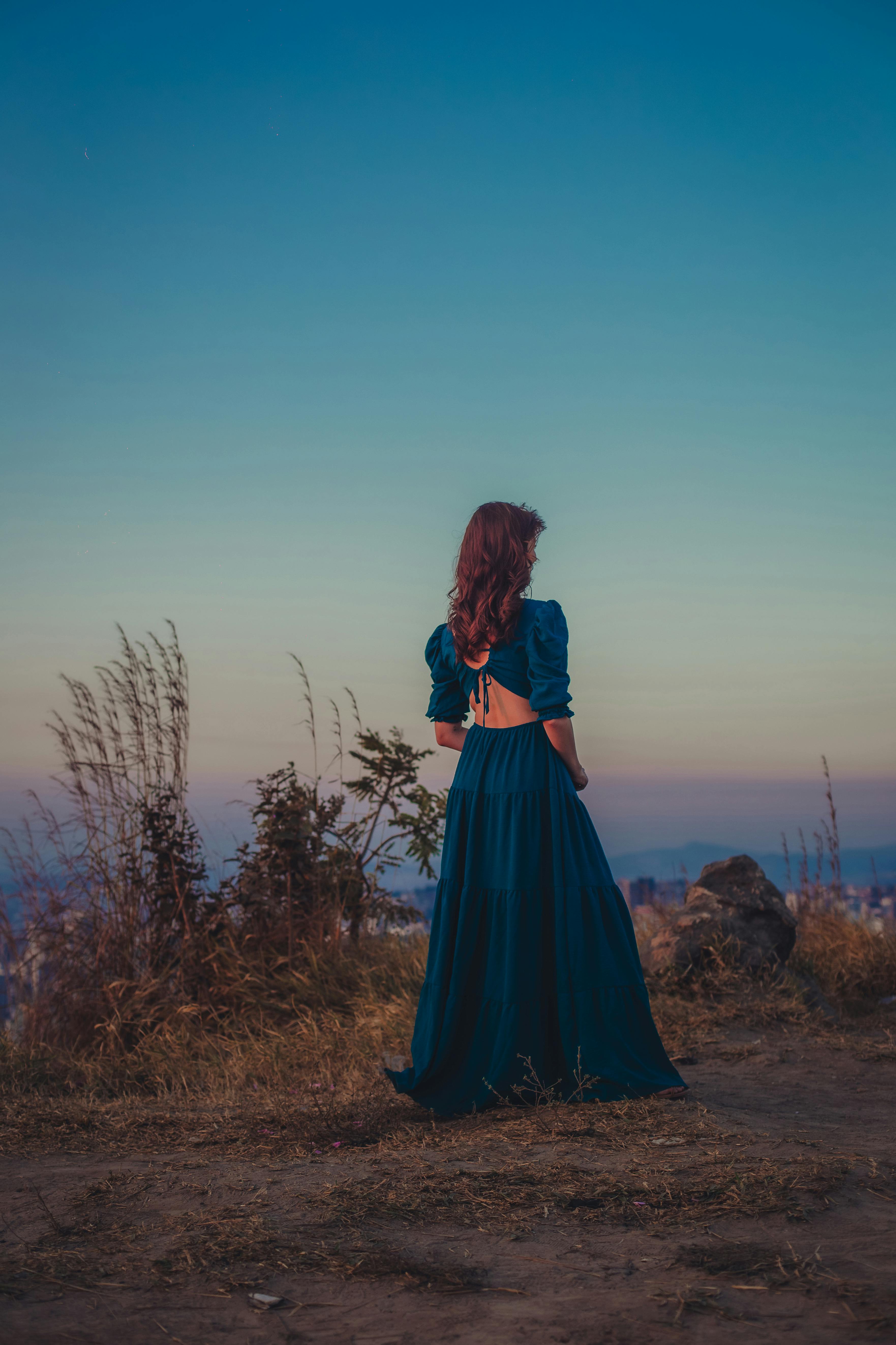 Romantic portrait of a woman in a blue dress during sunset in Belo Horizonte, Brazil, capturing the serene autumn atmosphere.