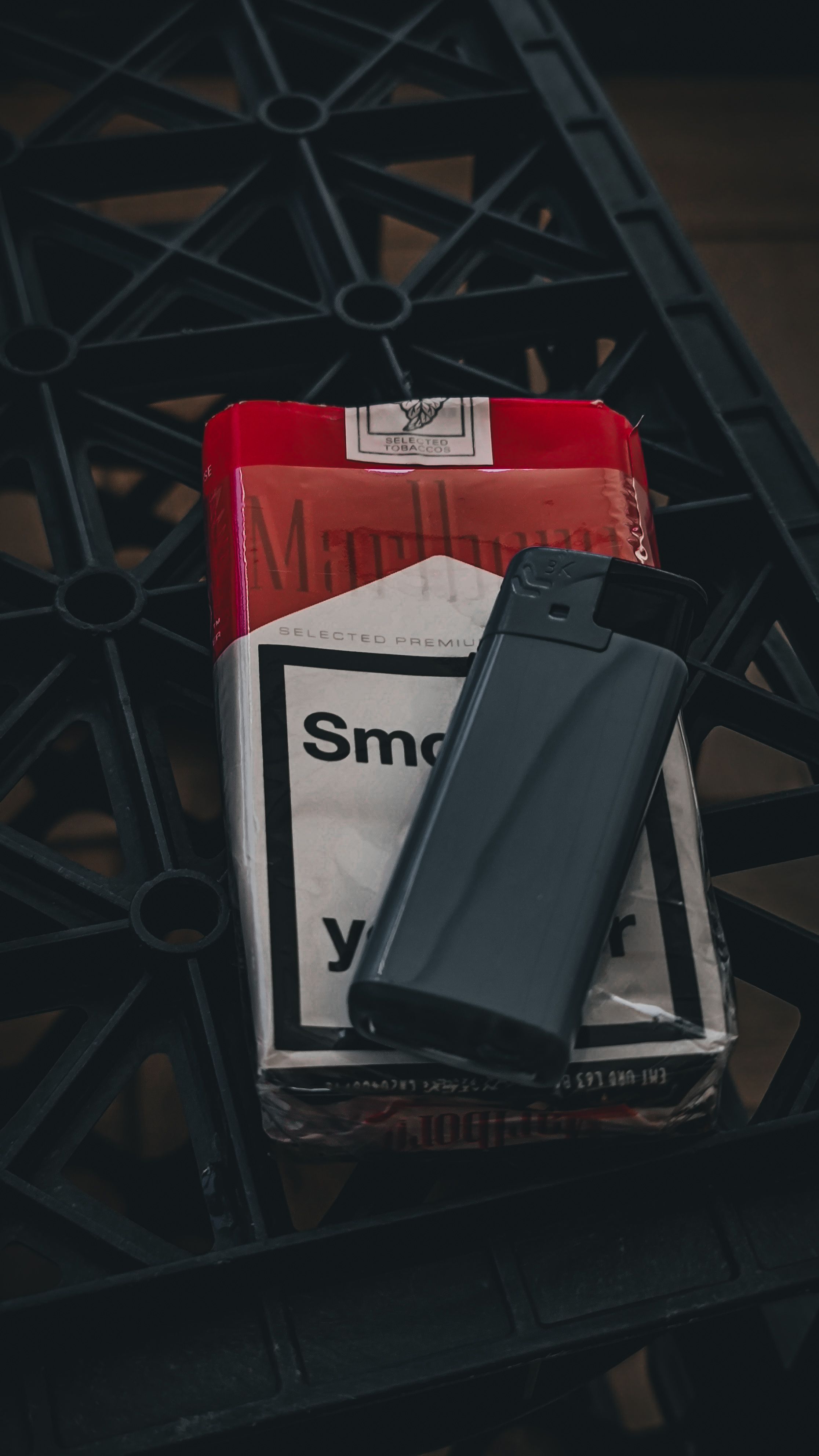 Free Close-up of a red and white cigarette pack with a black lighter on a textured surface. Stock Photo