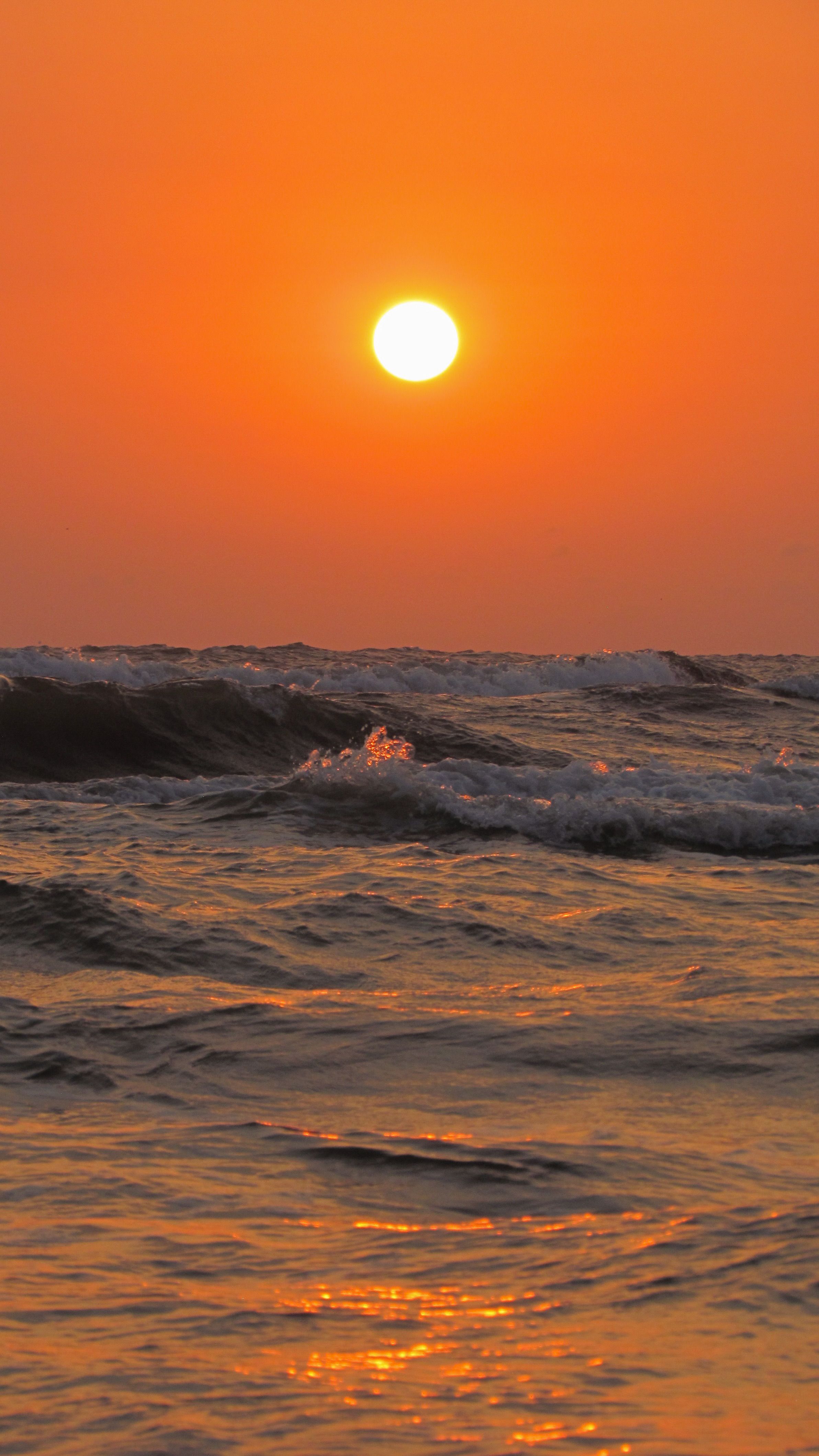 Beautiful sunset over the ocean with shimmering waves reflecting golden light.