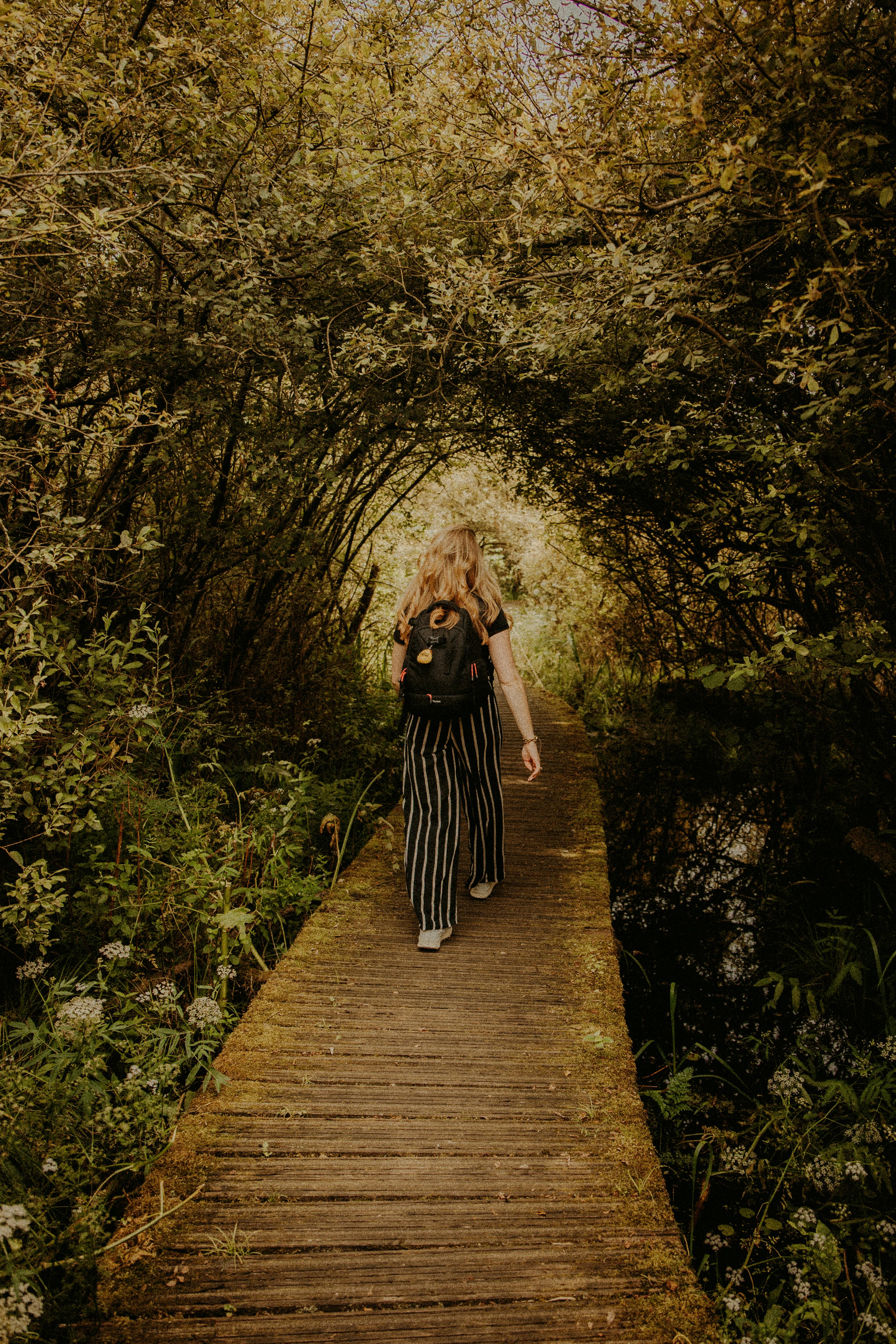 a woman walking down a wooden path in the woods