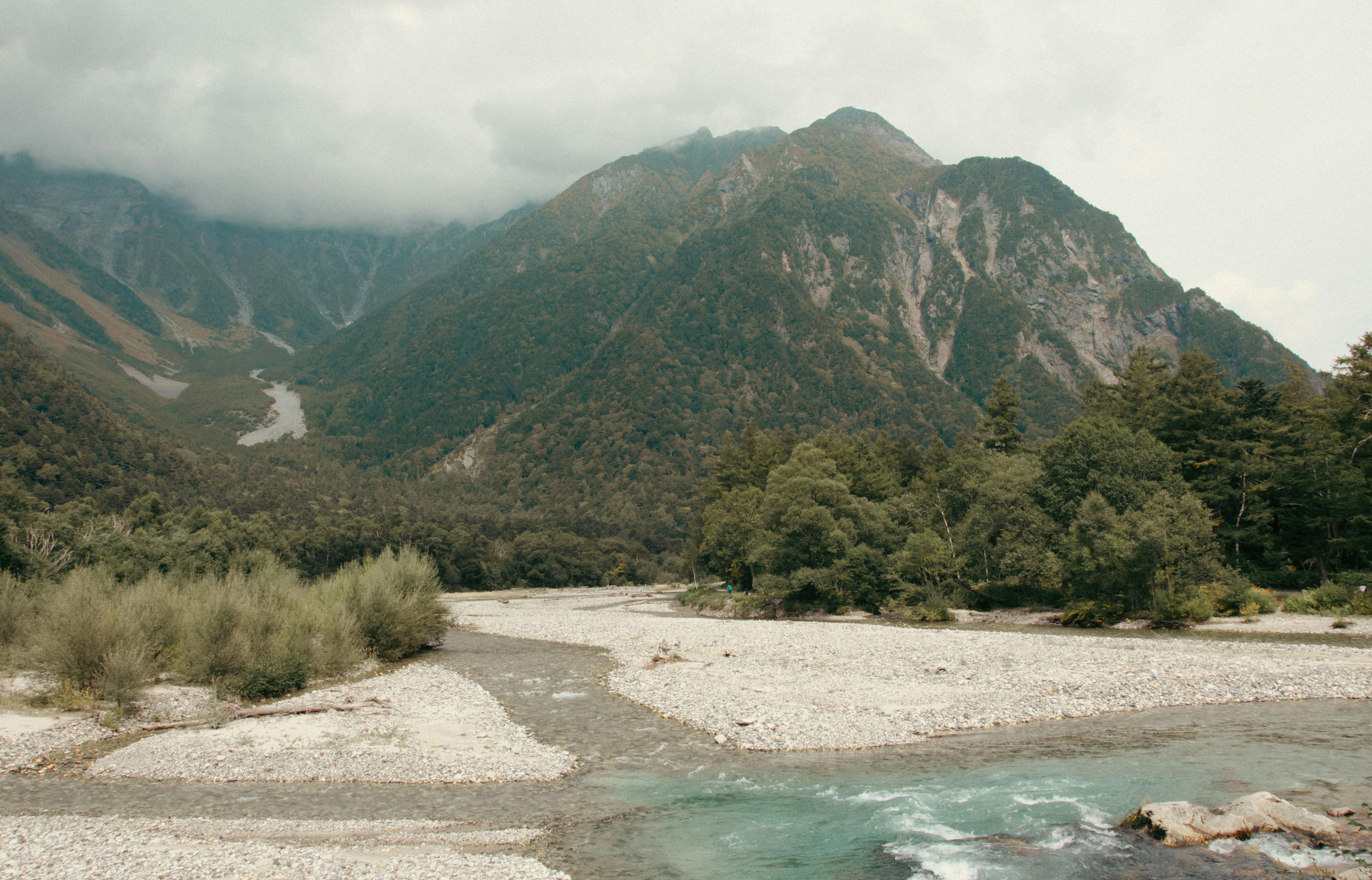 a river running through a valley with mountains in the background