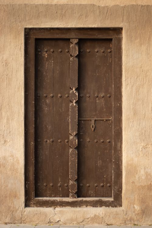 Free A rustic wooden door set in a weathered wall, showcasing traditional craftsmanship. Stock Photo