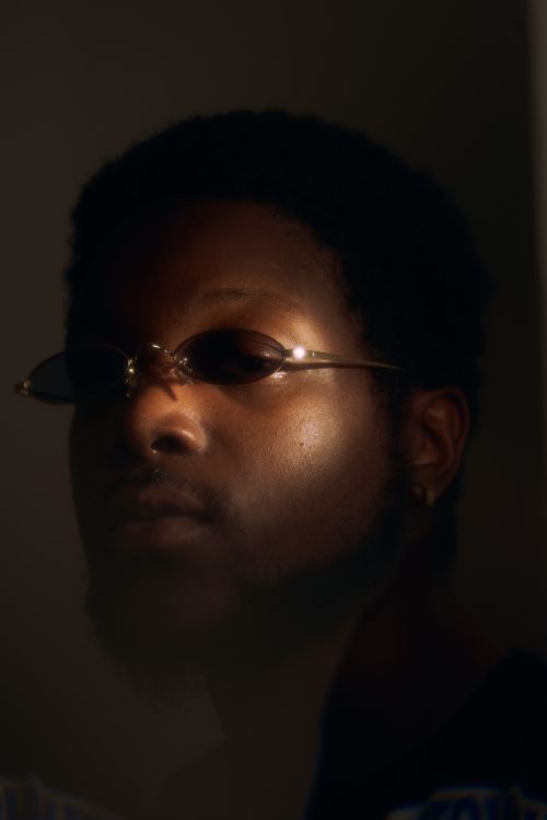 Free Artistic and moody portrait of a man wearing sunglasses with a dramatic play of light and shadow. Stock Photo