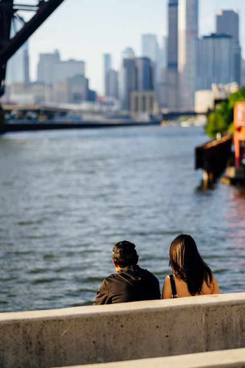 Two people sitting on a bench looking at the water · Free Stock Photo