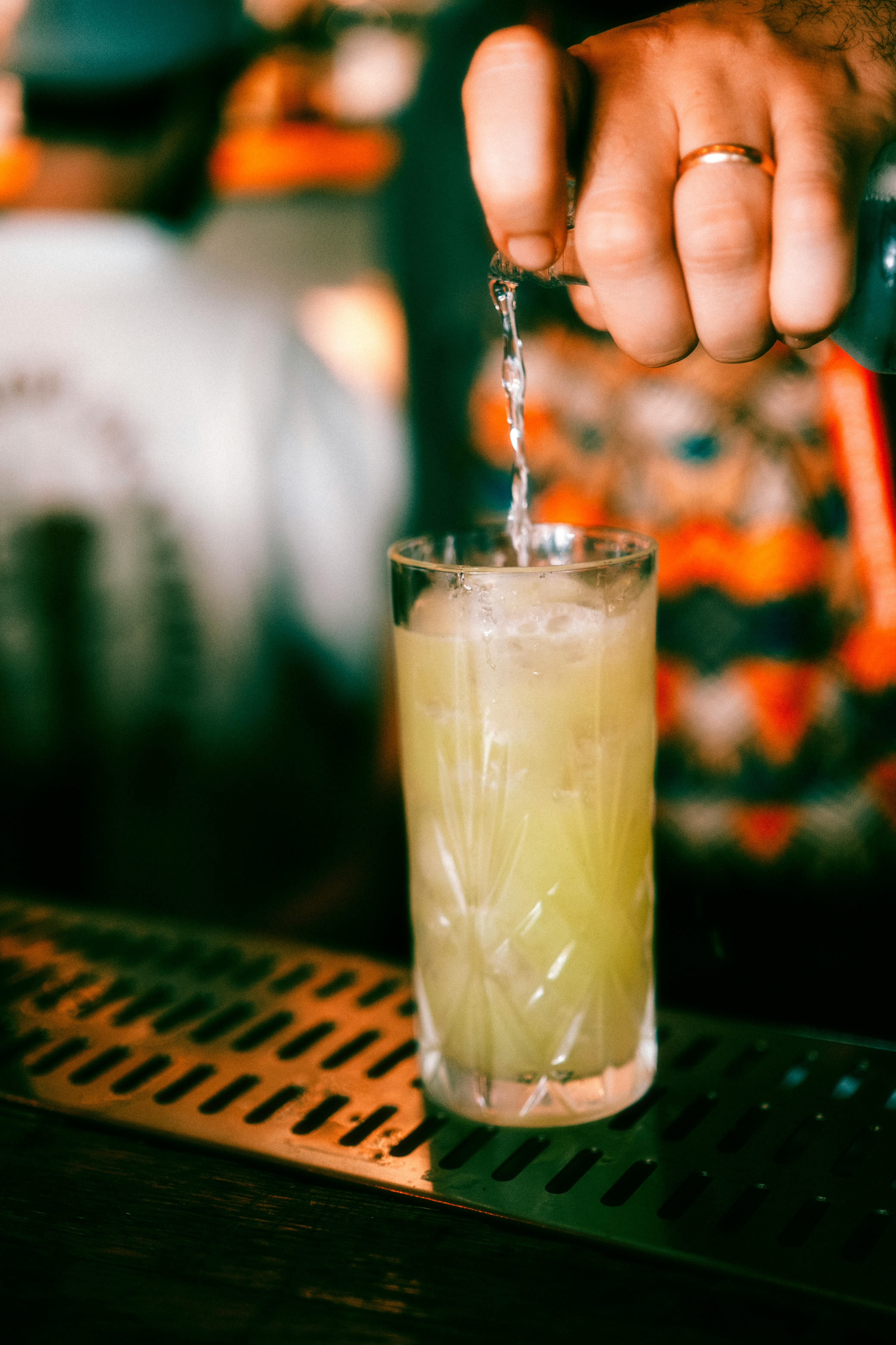 a person pouring a drink into a glass