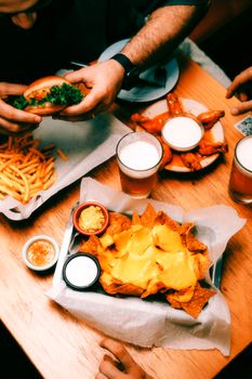 Vibrant dinner scene featuring nachos, burgers, fries, and craft beer in a cozy restaurant setting.