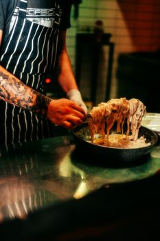 Chef skillfully cooks pasta in a restaurant kitchen, showcasing culinary expertise and artistry.