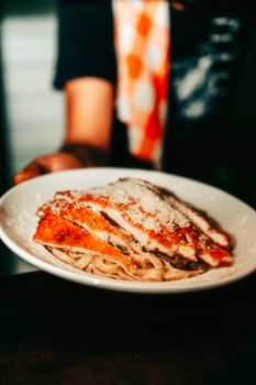 A delicious plate of chicken parmesan served over creamy tagliatelle pasta topped with grated cheese.