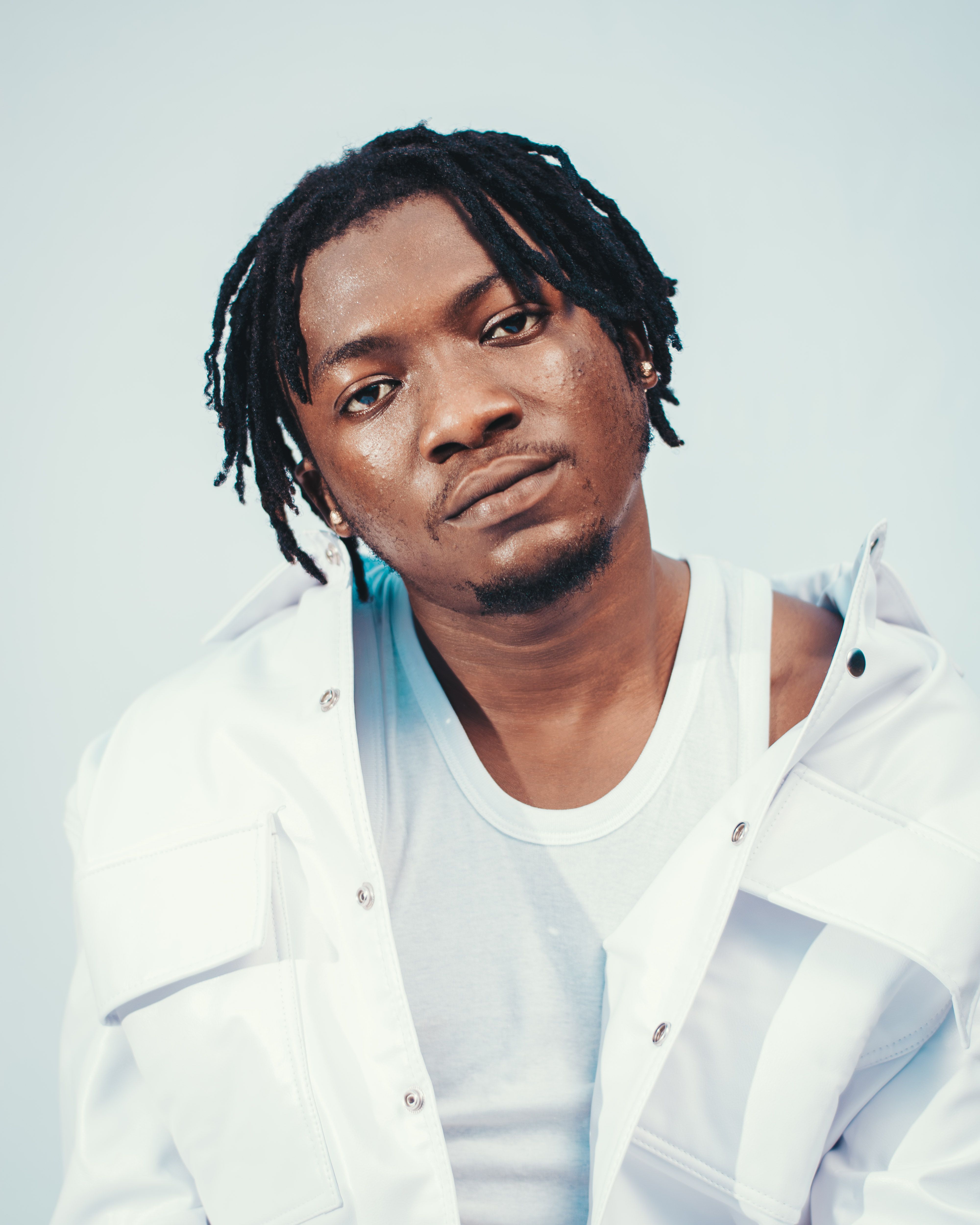 Close-up of a fashionable man wearing dreadlocks and white attire. Minimalist and contemporary style.