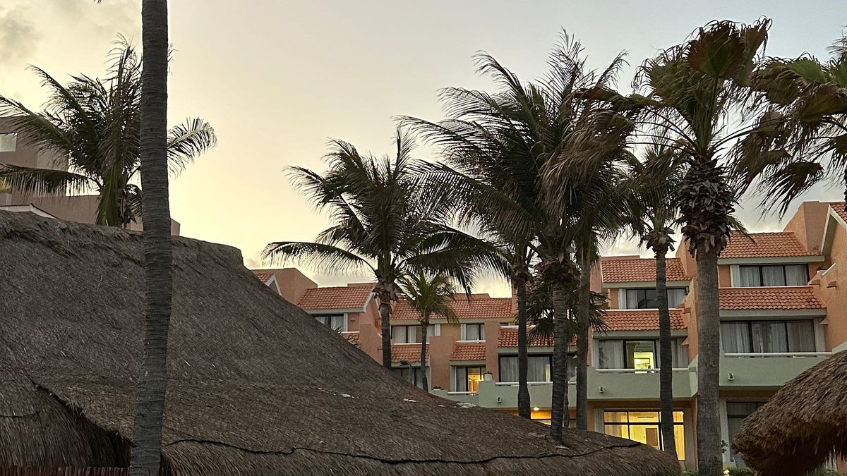 Palm trees and resort buildings at sunset in Cancun Mexico