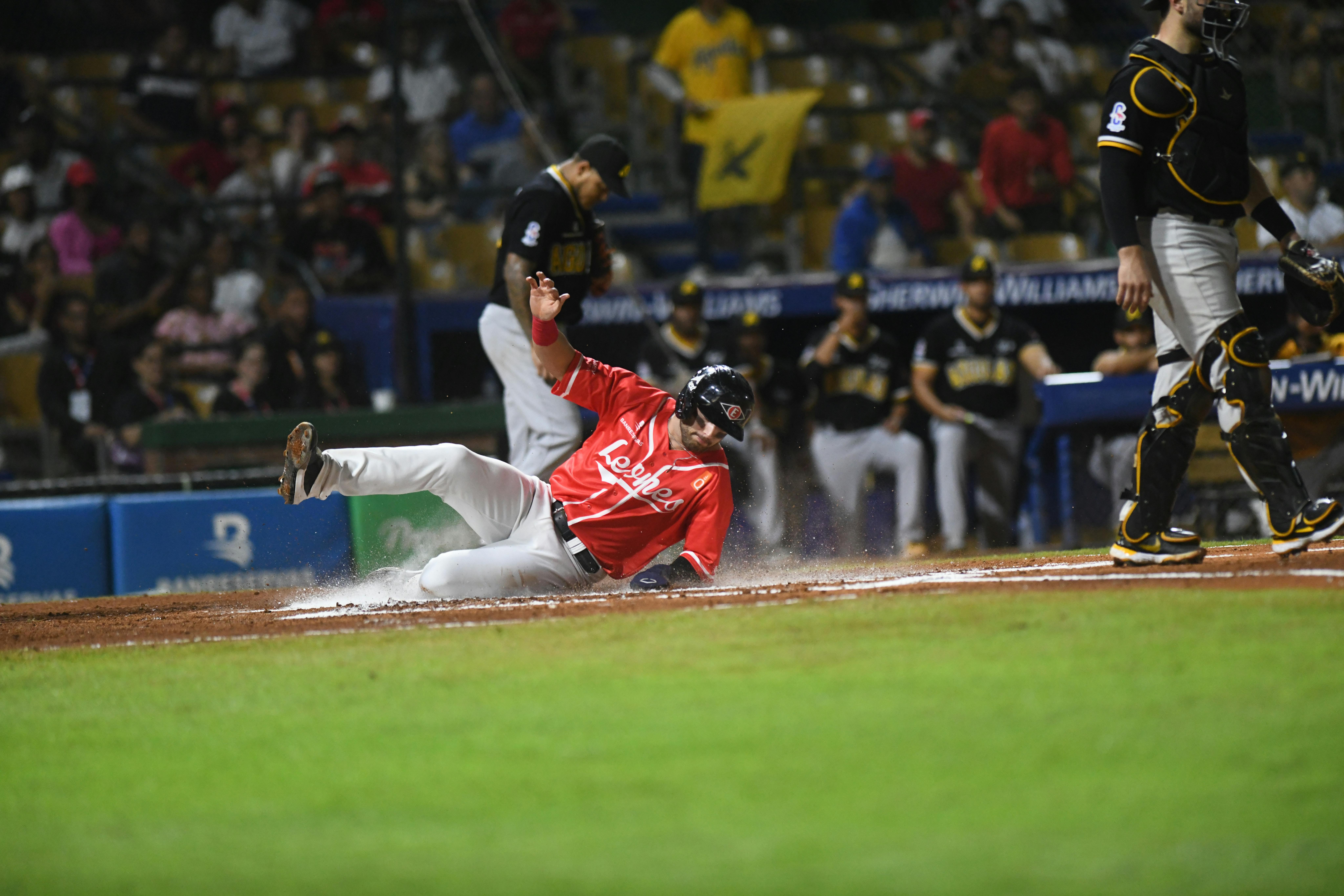 Sliding baseball player during an exciting game in Santo Domingo stadium.