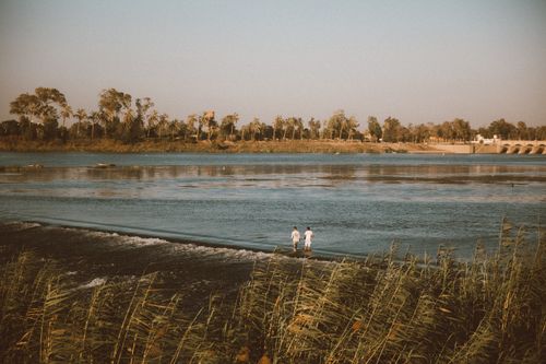Free Peaceful riverside view with two people along the Nile in Egypt during sunset. Stock Photo