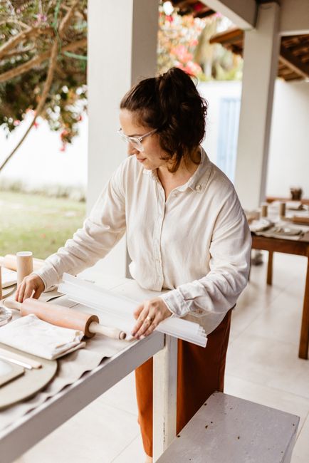 A woman in a cozy kitchen setting rolls out dough, surrounded by baking tools and warm ambiance.