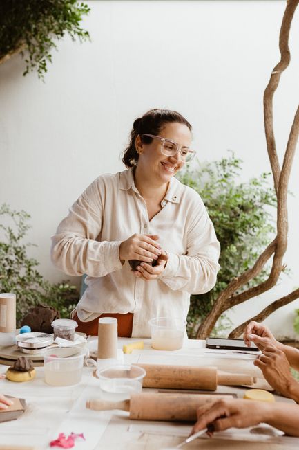A woman enjoying pottery making with others in a creative workshop setting.