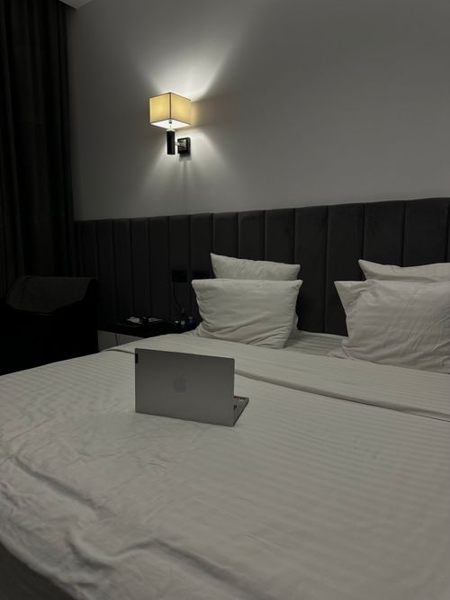 Free Luxurious hotel room featuring a double bed and a laptop, perfect for business travel. Stock Photo