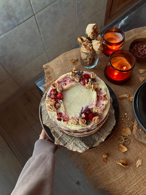 Free A delicious berry layer cake adorned with flowers, surrounded by candles and rustic decor. Stock Photo