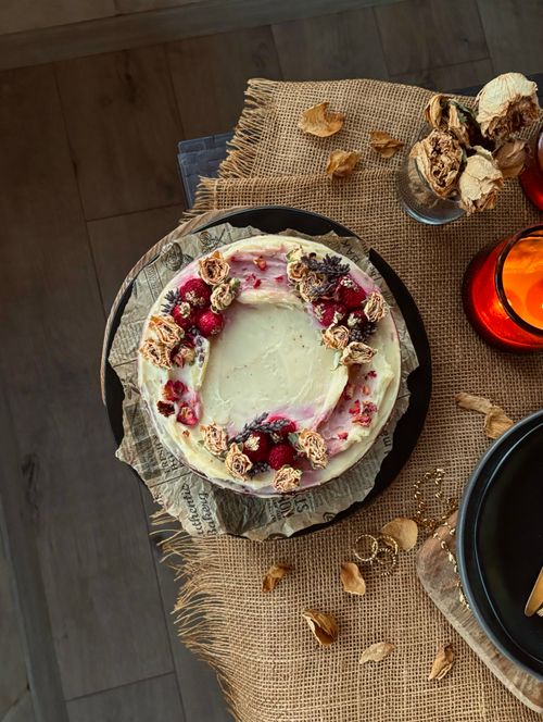 Free A rustic berry-topped cake on a wooden table, surrounded by festive decor. Stock Photo