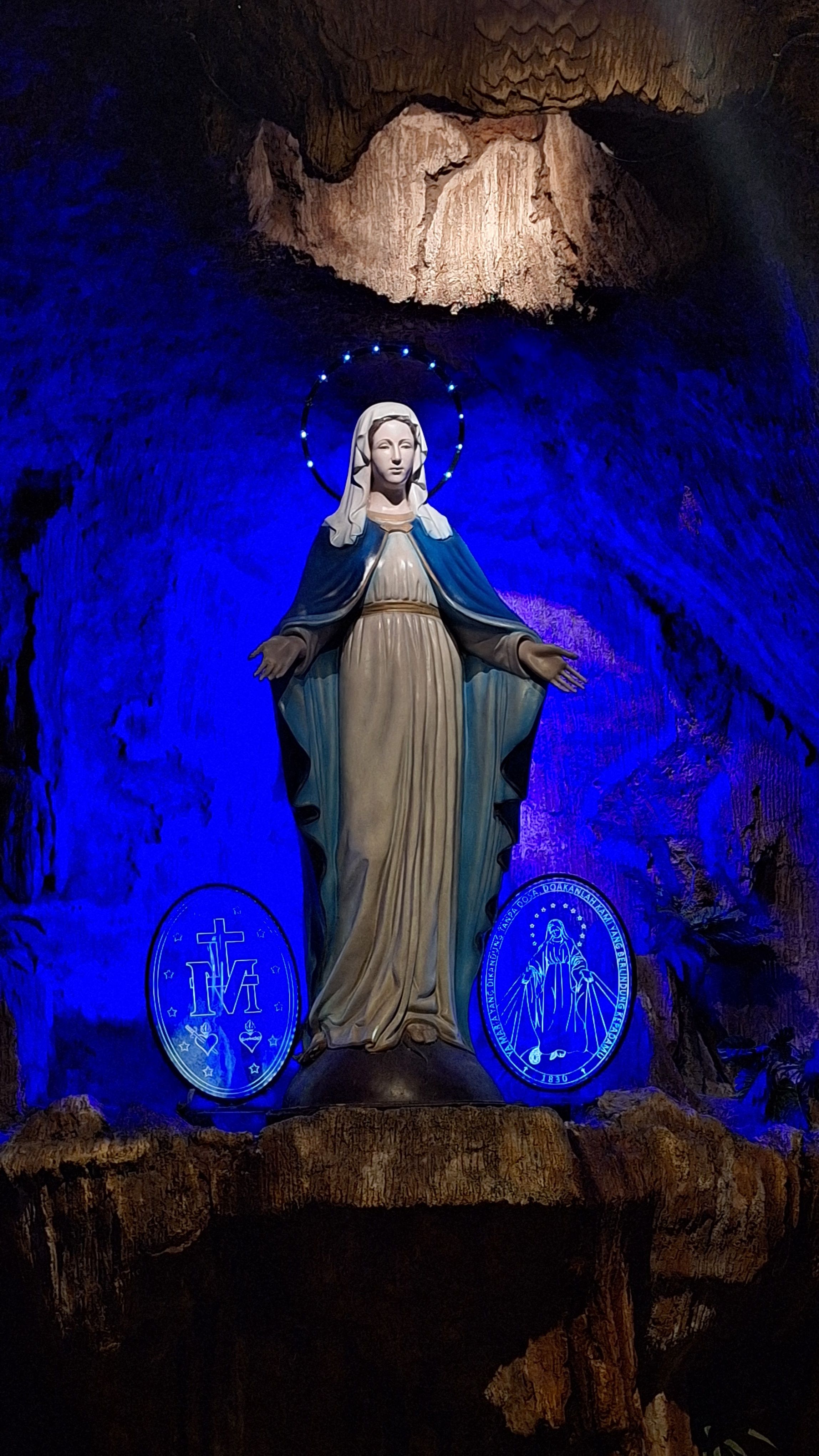 A serene Virgin Mary statue lit with blue backlight, symbolizing peace and spirituality.
