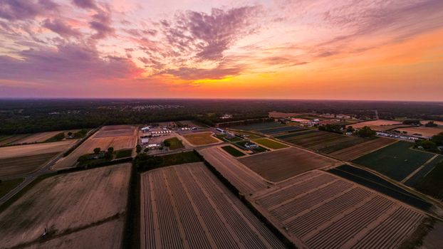 A breathtaking aerial view of a vast cropland landscape under a vibrant sunset sky.