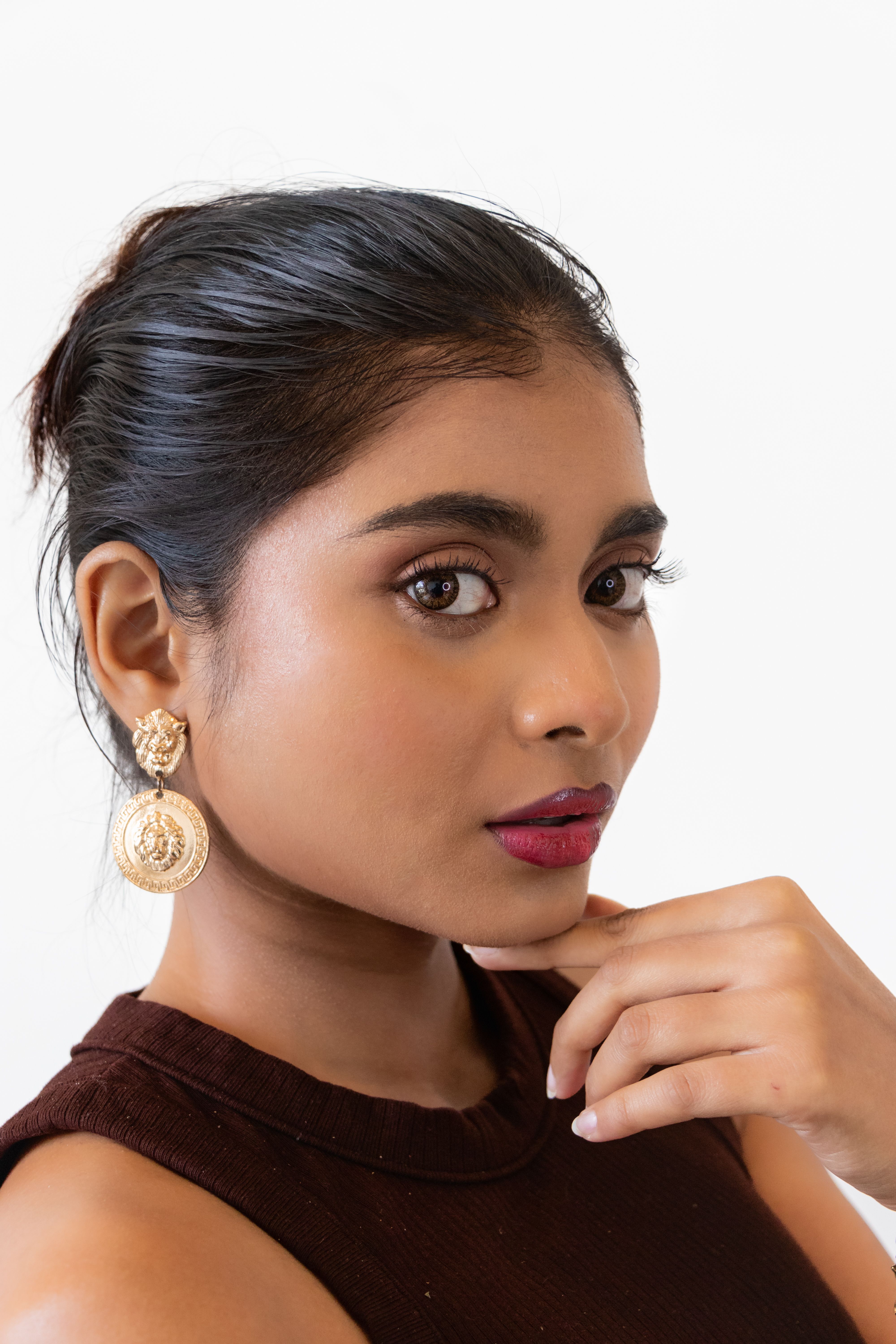 A woman wearing a brown top and gold earrings · Free Stock Photo
