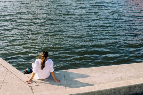 Free Woman enjoying a peaceful moment on a sunny day by the water in Chicago. Stock Photo