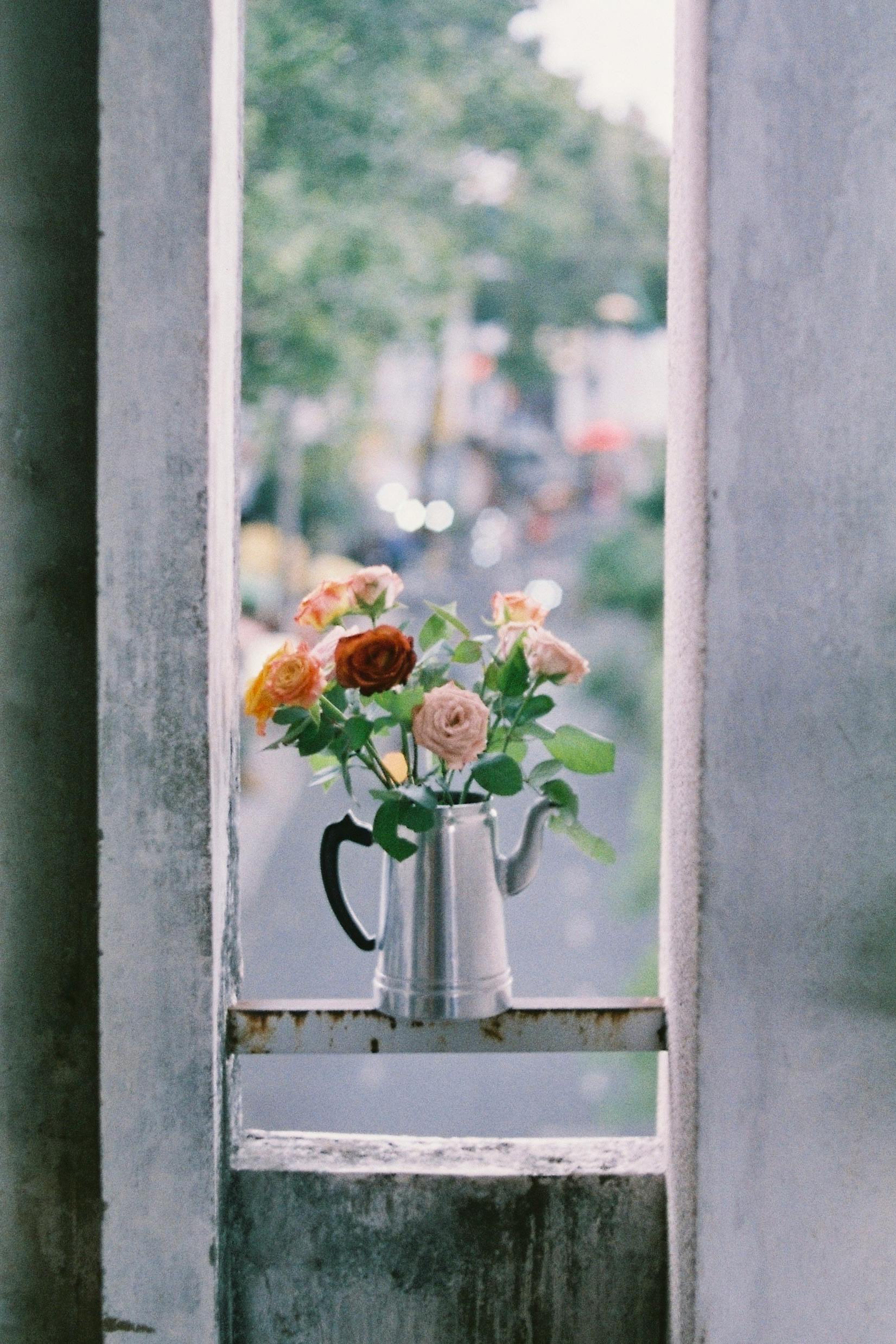 Charming rustic floral display in a watering can by a window, perfect for summer vibes.