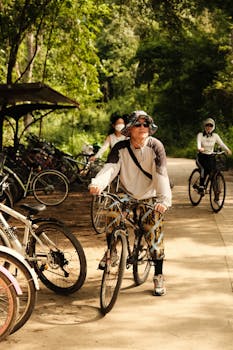 Cyclists riding through a lush forest path, enjoying outdoor leisure and recreation in daylight.