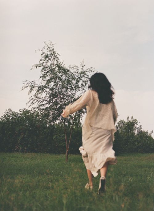 Free A woman enjoys a peaceful run through a lush, green field on a serene day. Stock Photo