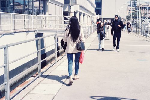 Free Street view of young adults walking along an urban sidewalk in daylight. Stock Photo