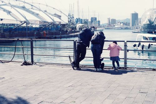 Free A family of three admiring the cityscape at a bustling harbor on a sunny day. Stock Photo