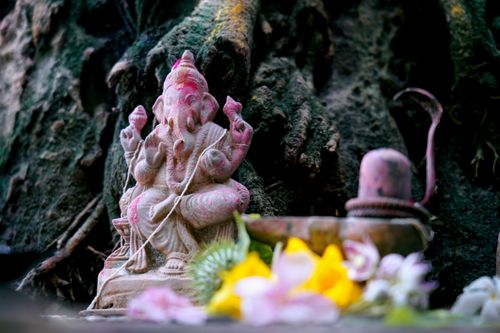 Free A serene Ganesh statue outdoors, adorned with vibrant flowers and natural surroundings. Stock Photo