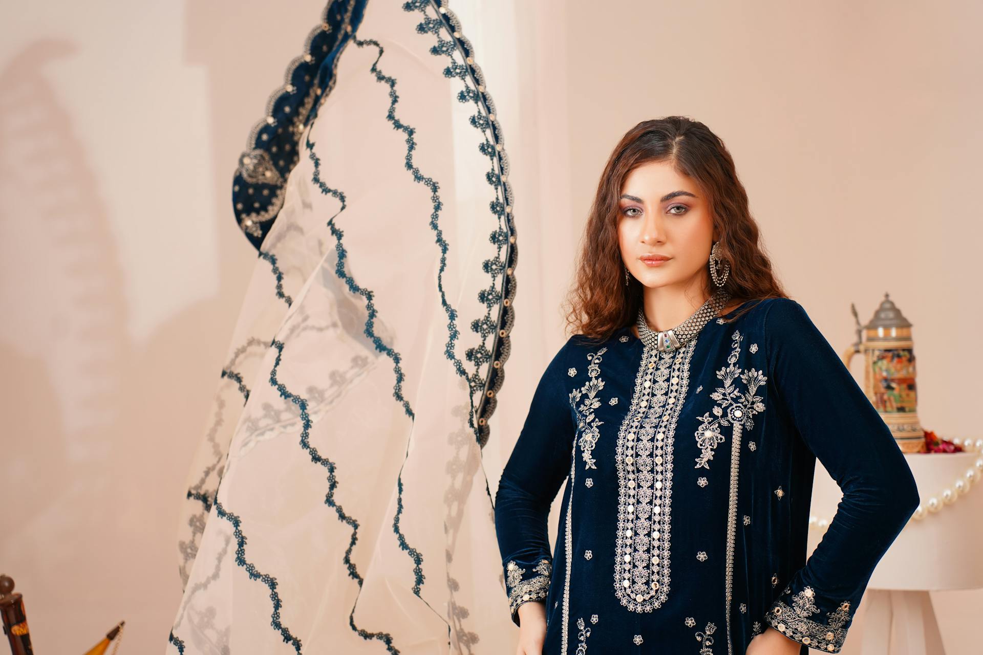 A beautiful woman modeling an elegant Eastern dress in a studio setting.