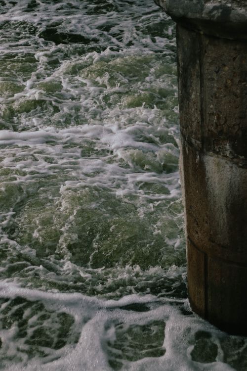 Free Powerful ocean waves crashing against a pier, creating mesmerizing foam patterns. Stock Photo