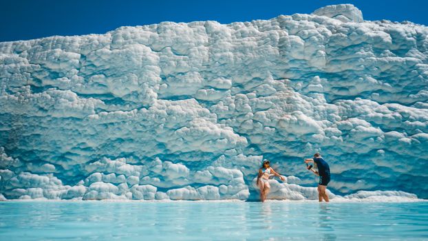 Visitors relax in the natural travertine pools of Pamukkale, a famous UNESCO World Heritage site in Turkey.