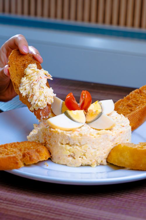 Free A close-up of a savory egg and cheese spread topped with tomatoes and served with toasted bread. Stock Photo