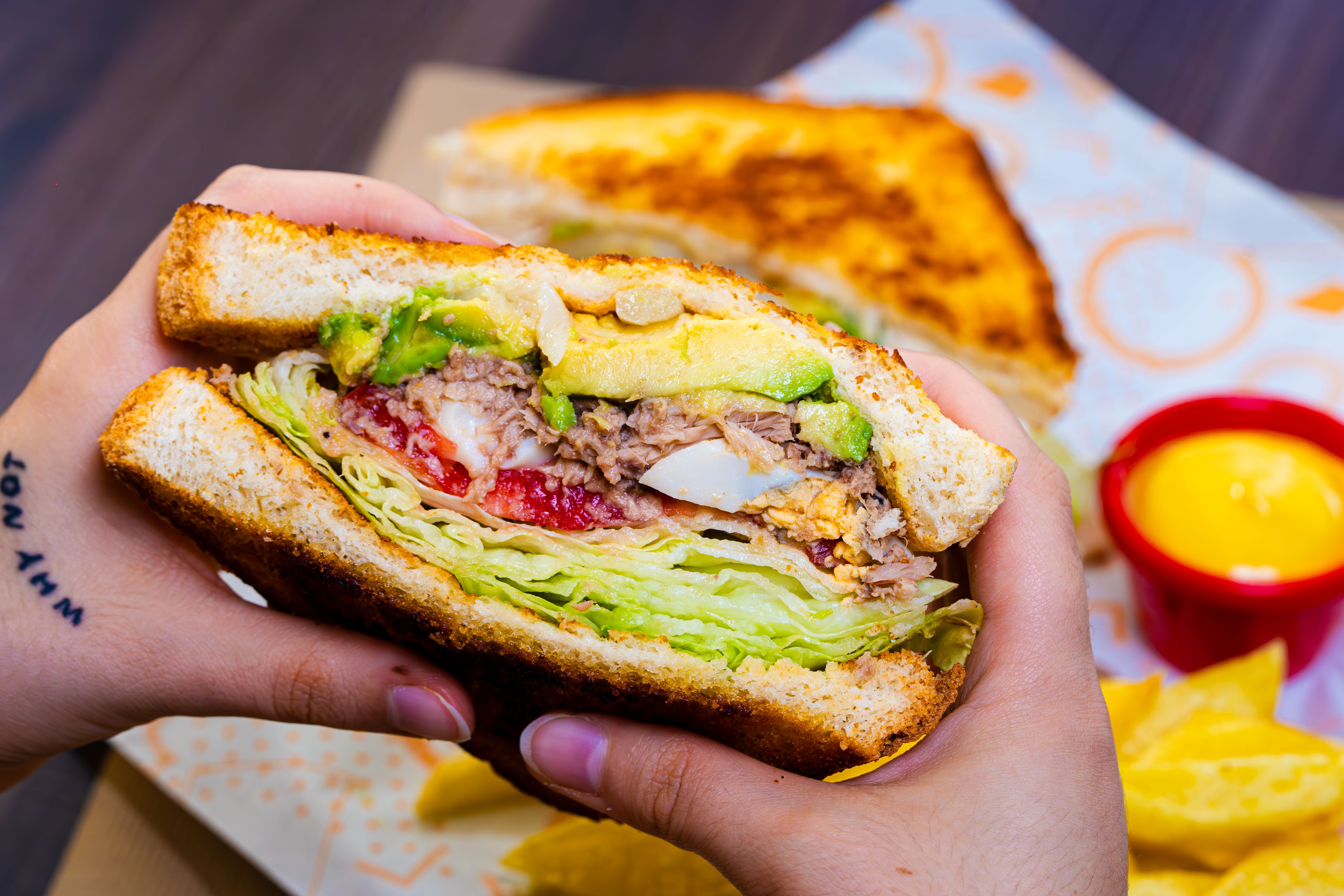 Free Delicious veggie sandwich with avocado and chips, perfect for lunch or snack. Stock Photo