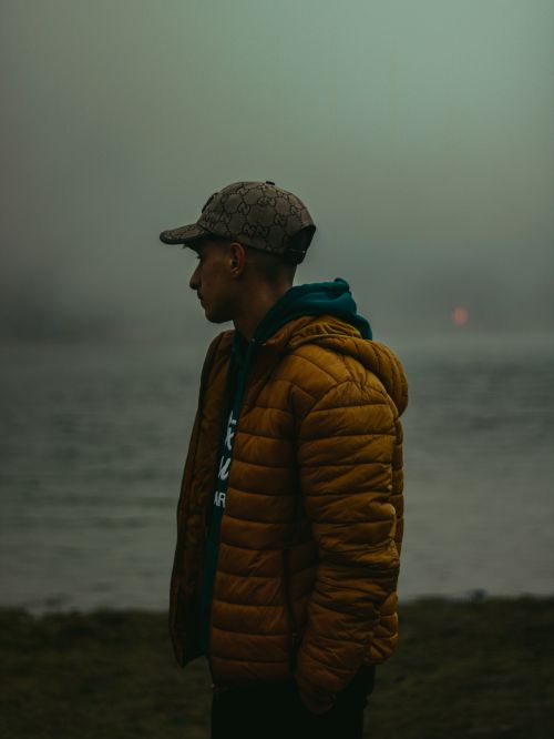 Free A person stands by a foggy lake at dawn, reflecting serenity and solitude. Stock Photo