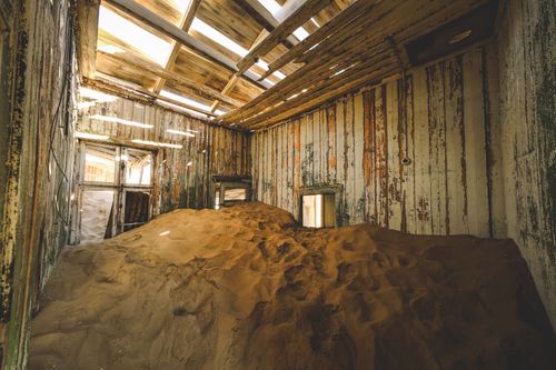 Free Interior of an abandoned house filled with sand, showcasing decay and natural invasion. Stock Photo