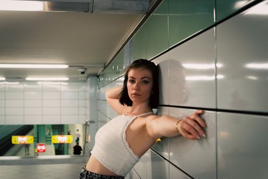 Fashionable woman poses confidently in a Berlin subway station, reflecting urban life.