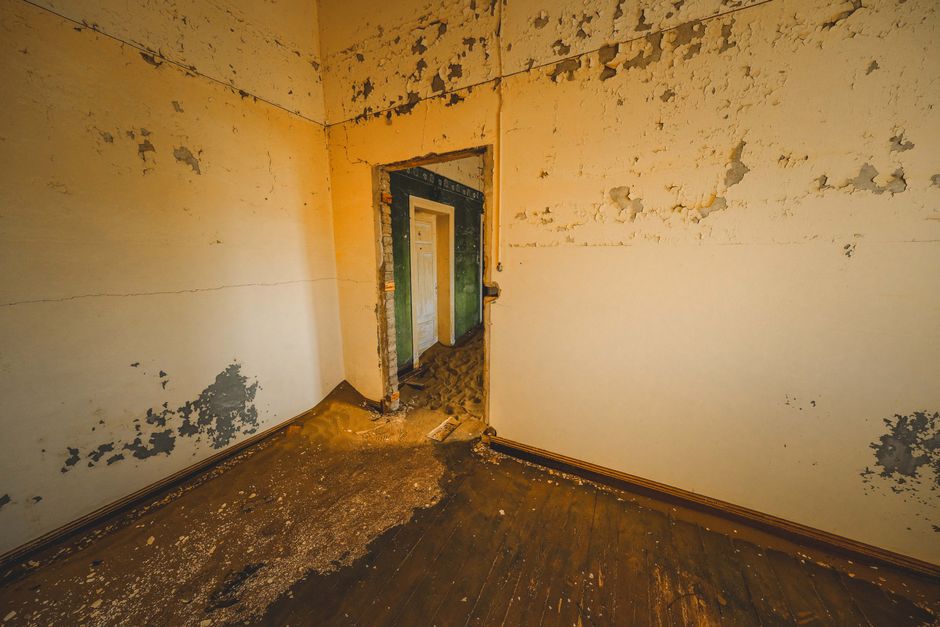 A decaying indoor room with peeling walls and an open doorway. Perfect for urban exploration themes.