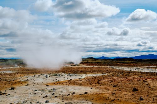 Free Wide view of a steaming geothermal field with cloudy sky, showcasing natural geothermal activity. Stock Photo