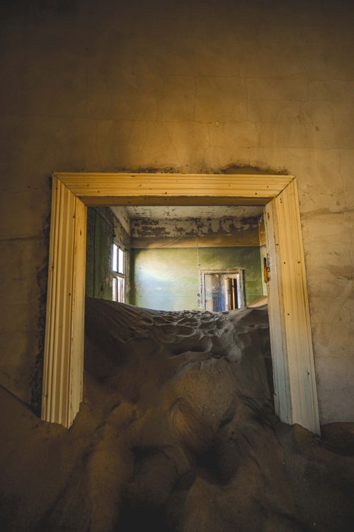 Free A haunting image of a sand-filled room in a decaying abandoned building, capturing an eerie atmosphere. Stock Photo