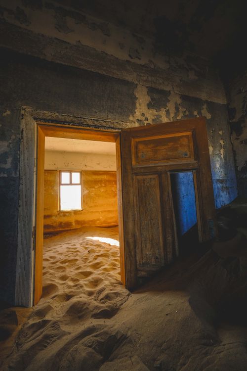 Free An abandoned building filled with sand and sunlight streaming through the doorway. Stock Photo
