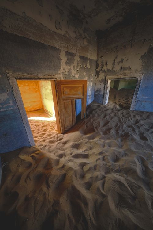 Free A mesmerizing view of an abandoned house interior filled with desert sand creating a surreal scene. Stock Photo