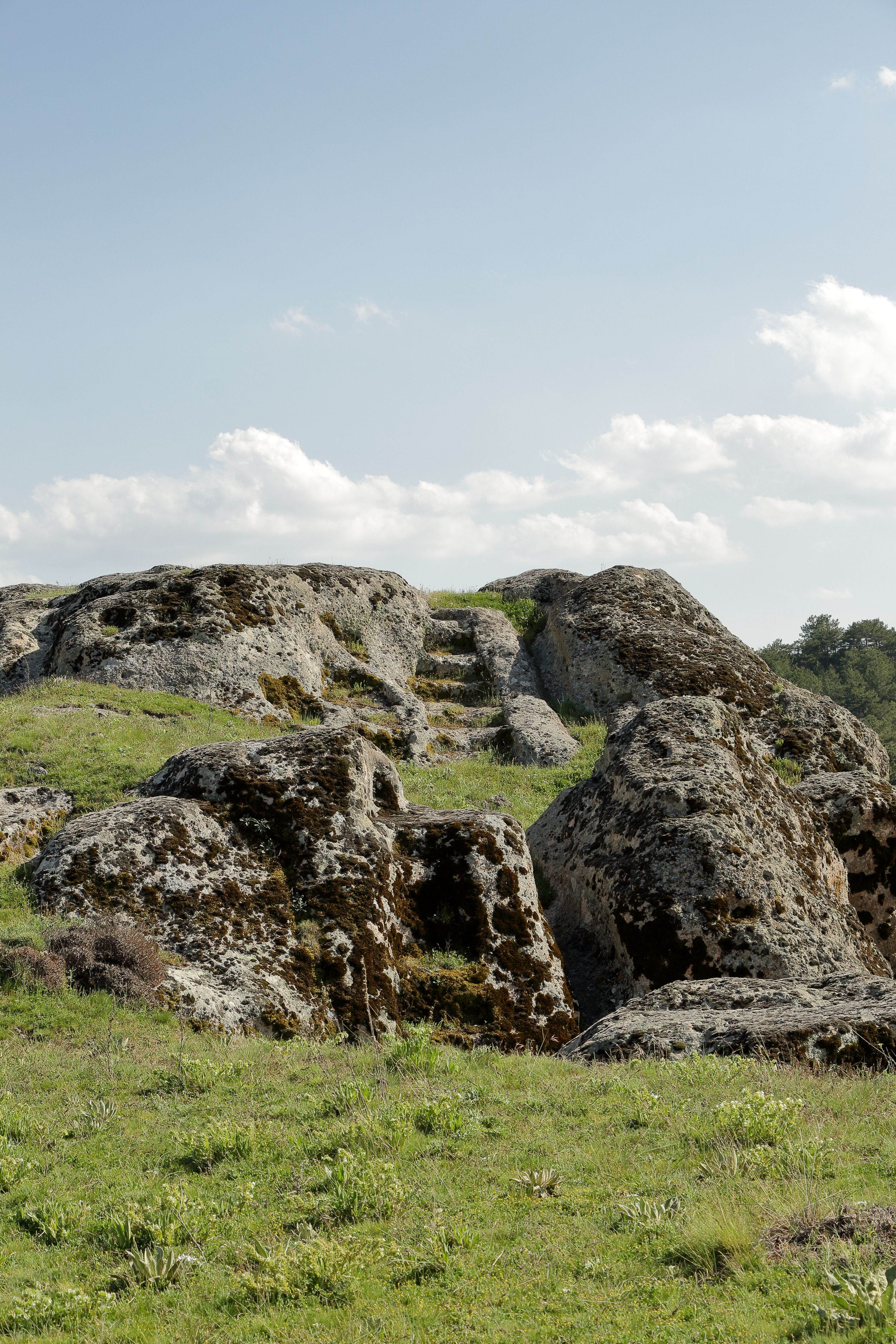 A large rock formation in the middle of a grassy field · Free Stock Photo