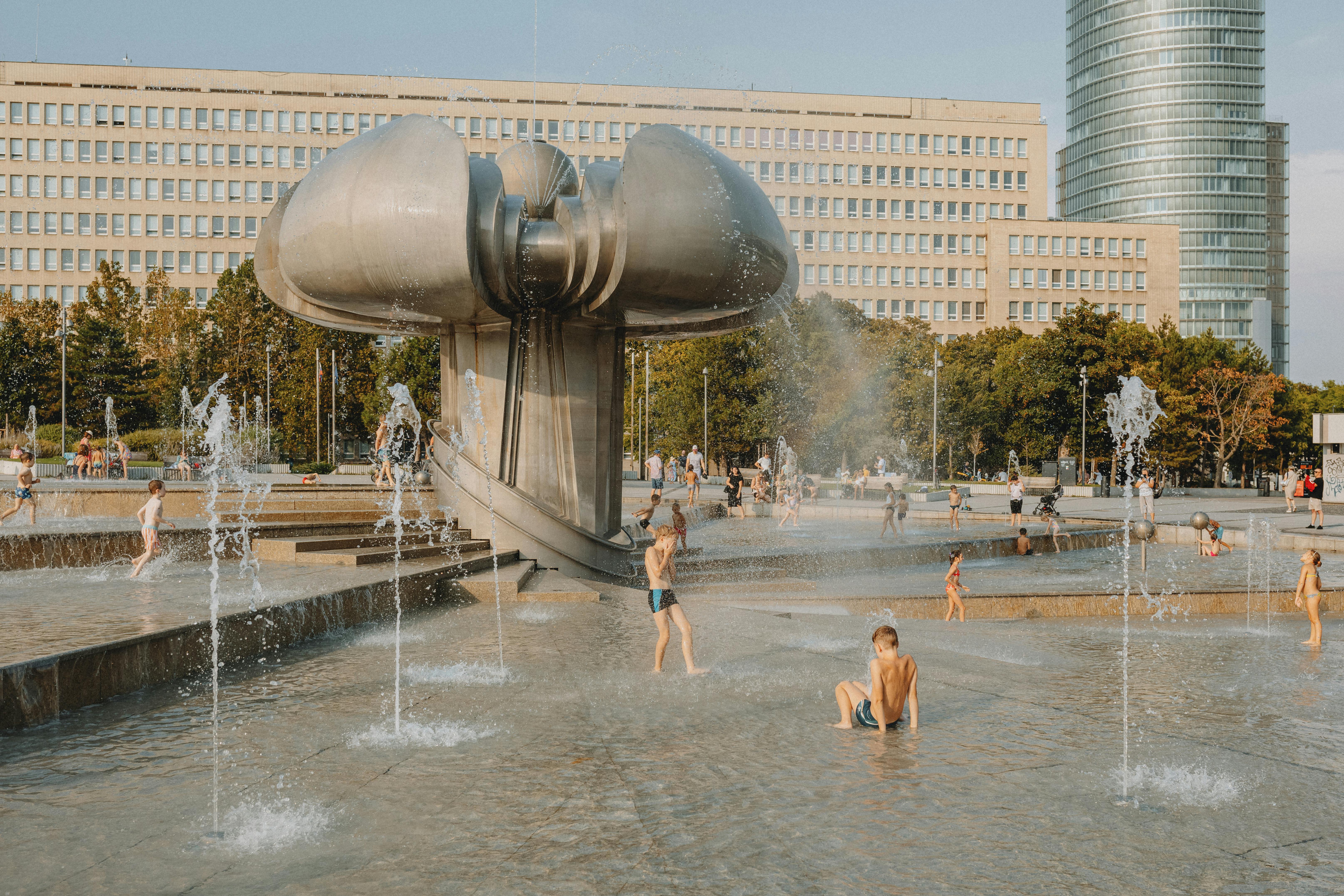 a fountain with people in it and a building in the background