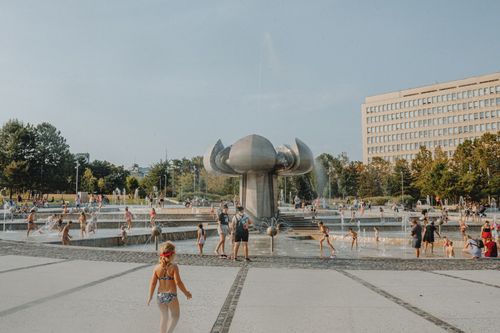 Free Children enjoying a sunny day at an urban park fountain with modern architecture. Stock Photo