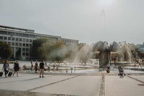 Free People enjoy a sunny day at a city fountain with mist and playful water jets. Stock Photo